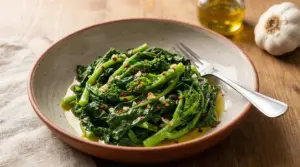 Piatto di cime di rapa saltate con aglio, olio extravergine e peperoncino su tavolo di legno